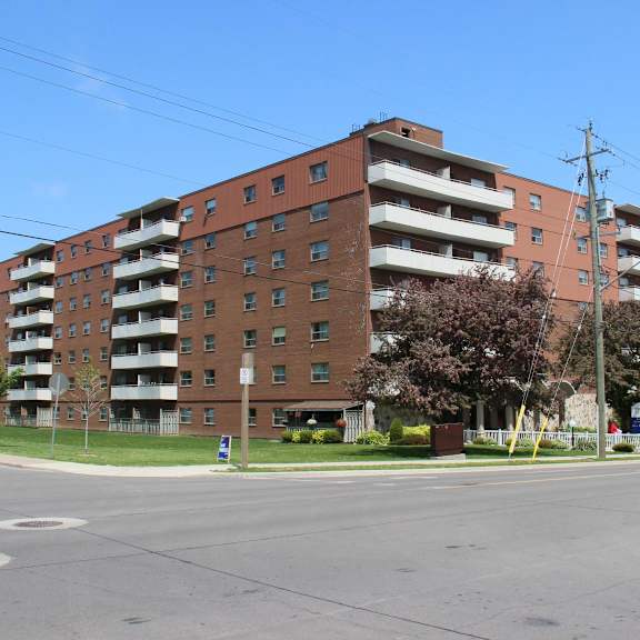 a large red brick apartment building with a parking lot in front.