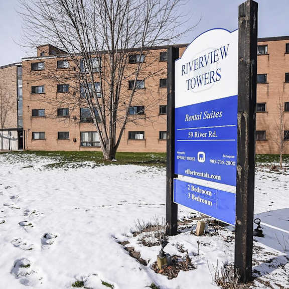 a sign for riverview towers stands in front of apartment buildings.
