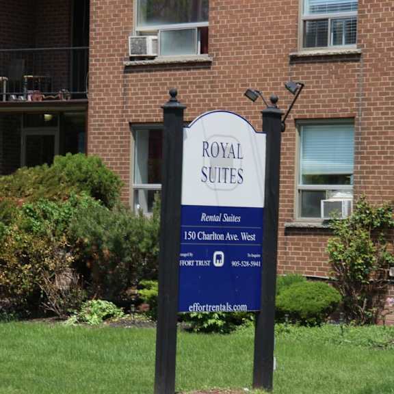 a sign for royal suites rental suites stands in front of a brick building.