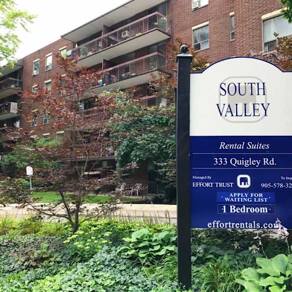 a sign for south valley apartments stands in front of a brick building.