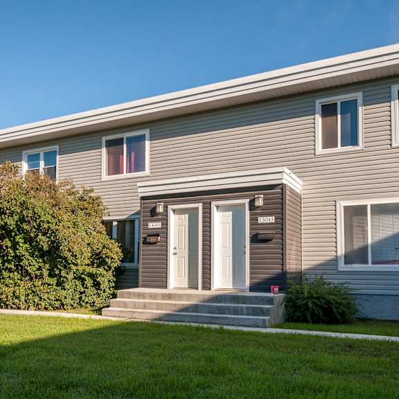 a grey house with a white door and windows.