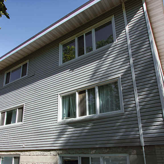 a grey house with a red brick building behind it.