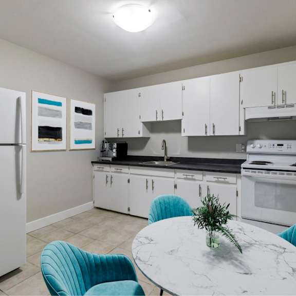 a kitchen with a white fridge, white cabinets, a white countertop, and a white island with a marble top.