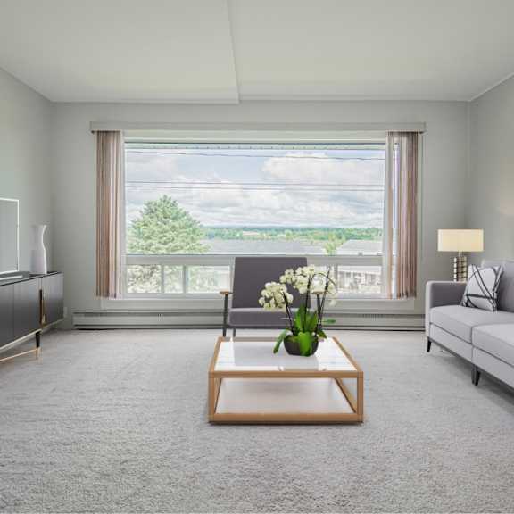 a modern living room with a grey carpet and a large window overlooking a lake.