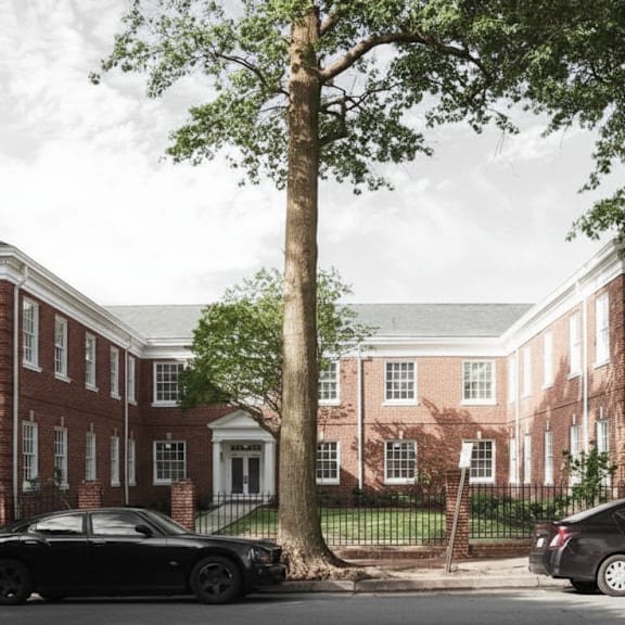 a black car is parked in front of a red brick building.