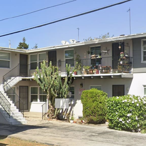 a grey and white two story house with a cactus in front.