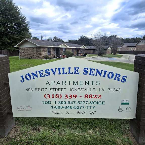 a sign for jonesville seniors apartments is displayed in front of a grassy area.