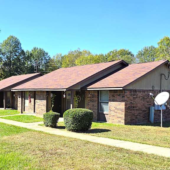 a house with a red roof and satellite dishes on the lawn.