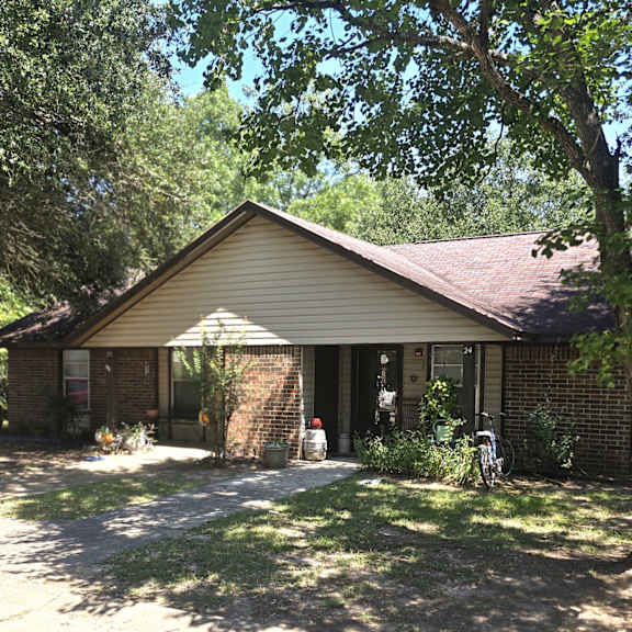a house with a brown roof and a white garage door is surrounded by trees.