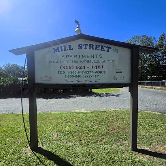 a sign for mill street apartments is shown in front of a grassy area.