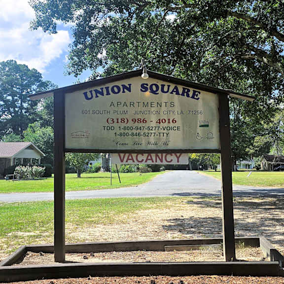 a sign for union square apartments is displayed in front of a grassy area.