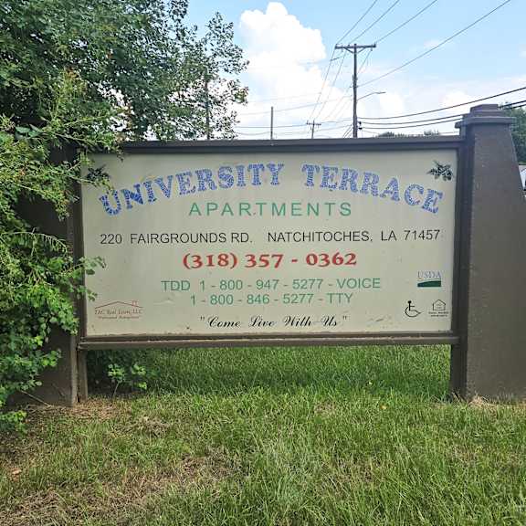 a sign for university terrace apartments is shown in front of some trees.