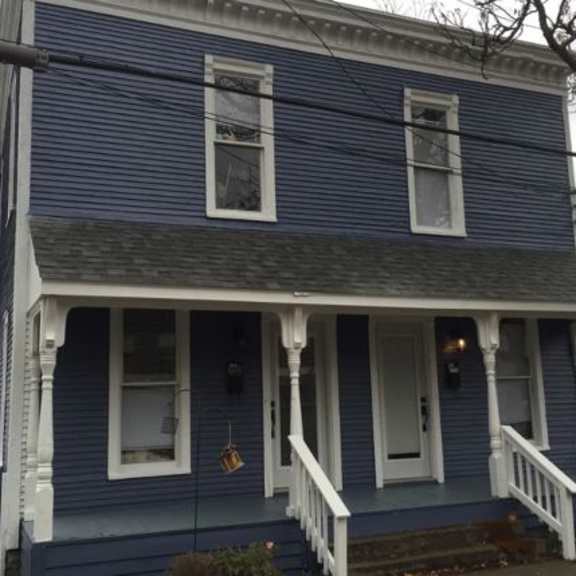 a blue house with white trim and a front porch.