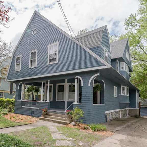 a blue house with a porch and a front yard.