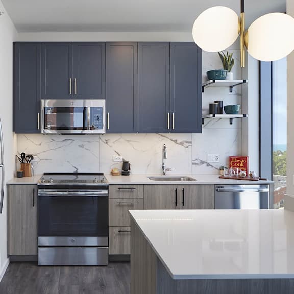 a modern kitchen with dark blue cabinets and stainless steel appliances.