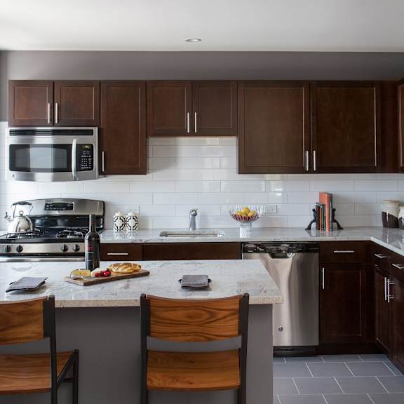 a kitchen with a white counter top and wooden chairs.