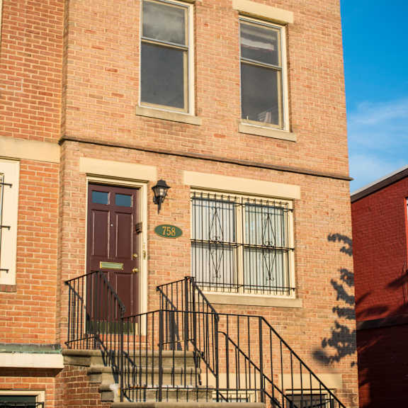 a red brick building with a black iron railing on the stairs.