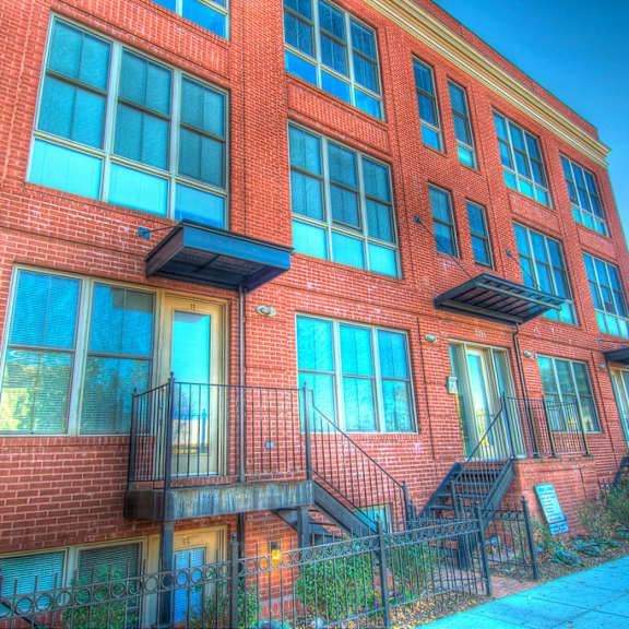 a red brick building with a balcony and a black railing.