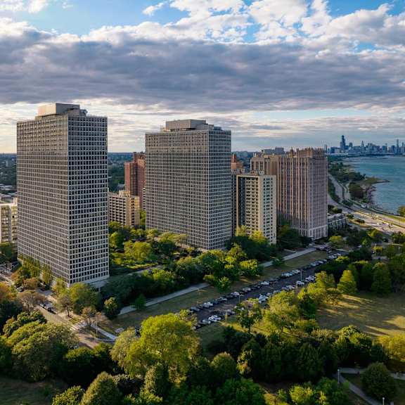 a cityscape with buildings, trees, and a body of water in the background.