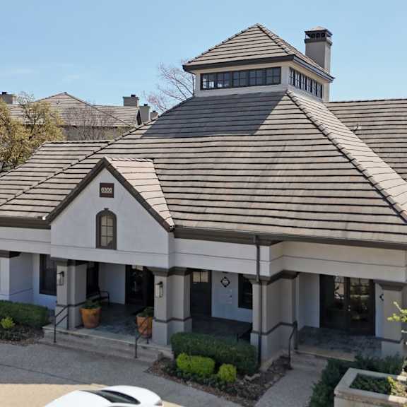 a leasing office with a brown roof and well-trimmed vegetation at jefferson place apartments in irving, tx