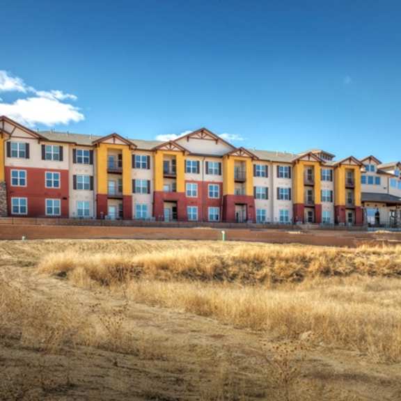 a large multi-story building with a red and yellow facade sits on a hill.