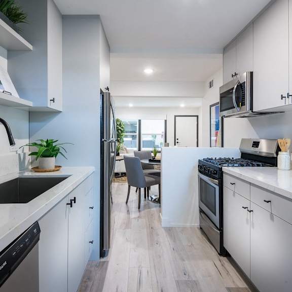 a modern kitchen with white cabinets and a wooden floor.