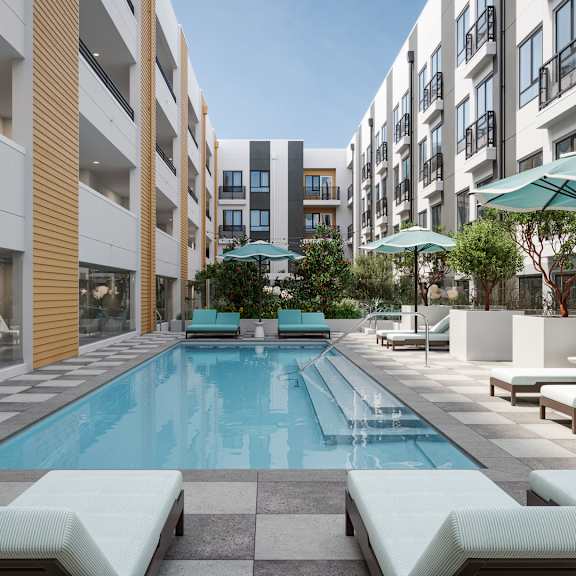 a swimming pool surrounded by lounge chairs and umbrellas in a courtyard.