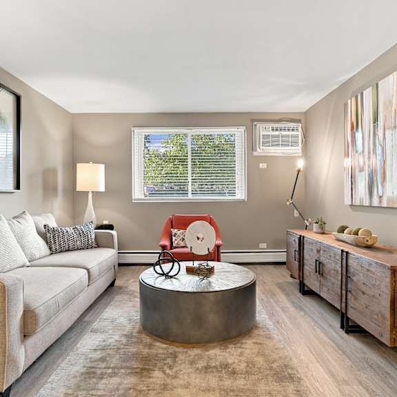 A living room with a white couch, a round table, and a red chair.