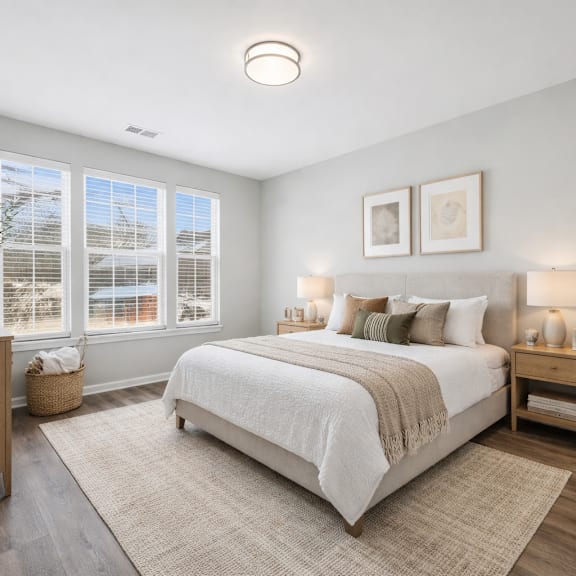 A bedroom with a large bed and a window with blinds.