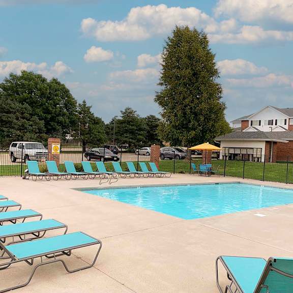 a pool with sun loungers and a building in the background.