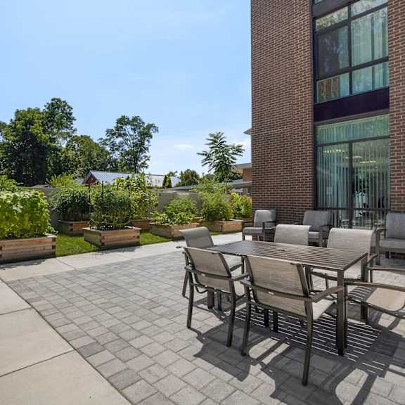 a patio with a wooden table and chairs and a brick building in the background