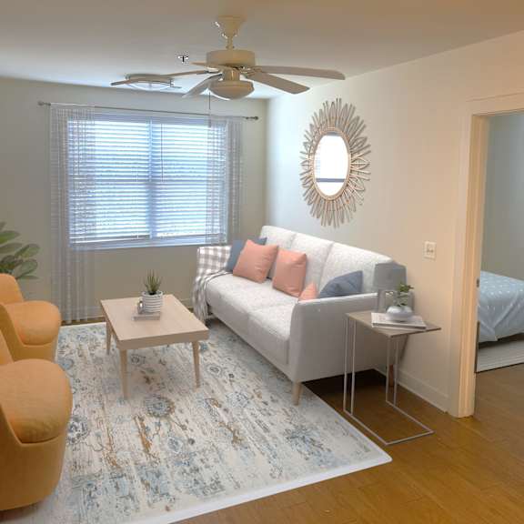 a living room with a white couch, a yellow chair, and a rug.