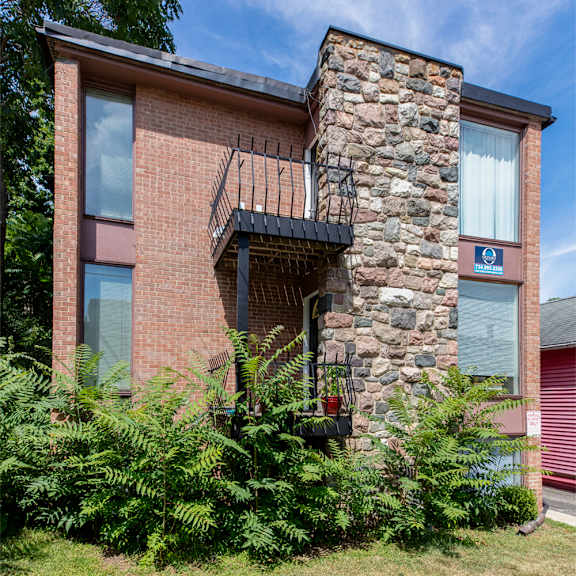 a red brick house with a balcony and a stone chimney.