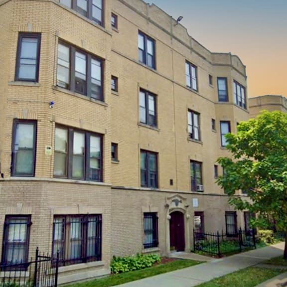 a brick apartment building with a tree in front of it