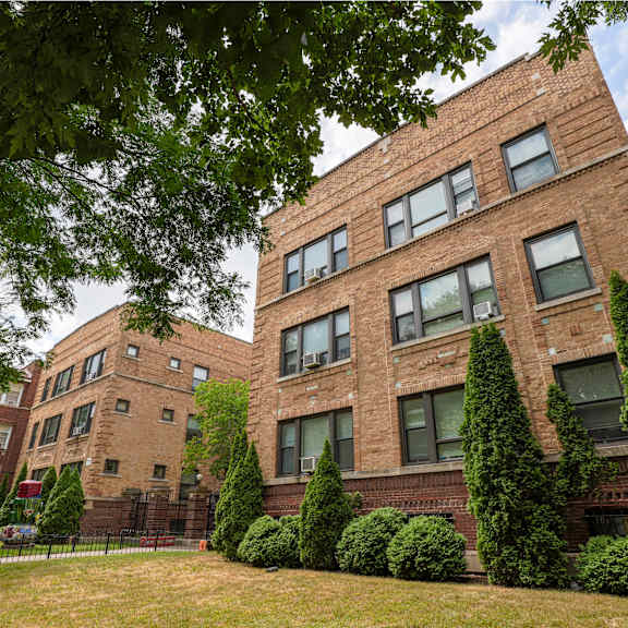 a red brick building with green trees in front.