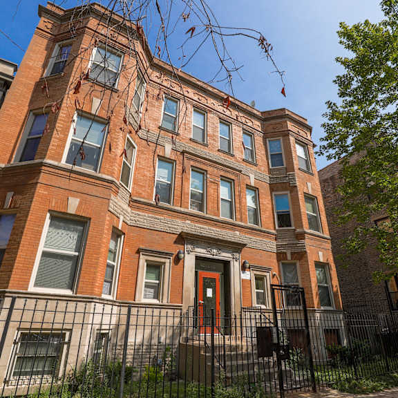 a red brick building with a black iron fence in front.