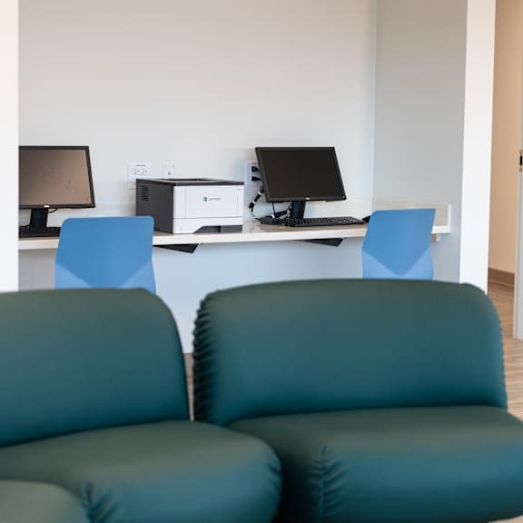 two green chairs are in front of a desk with two computers.