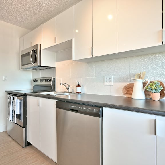a modern kitchen with white cabinets and stainless steel appliances.