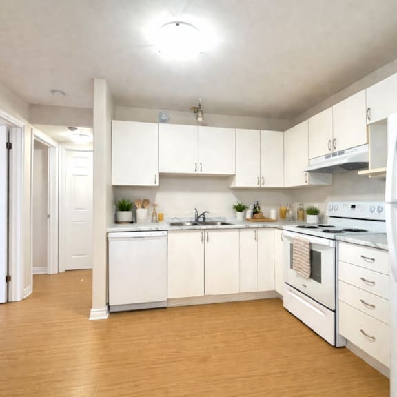 a kitchen with white appliances and wooden floors.