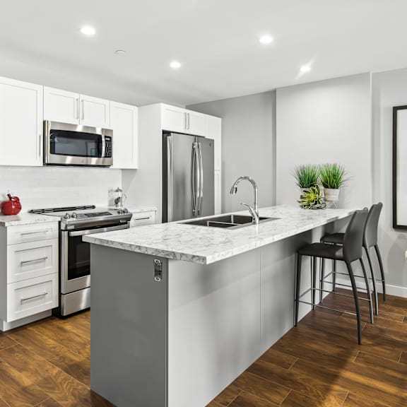 a modern kitchen with a marble countertop and stainless steel appliances.