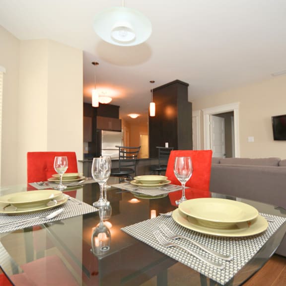 a modern dining room with a glass table set for two.