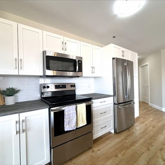 a kitchen with white cabinets and stainless steel appliances.