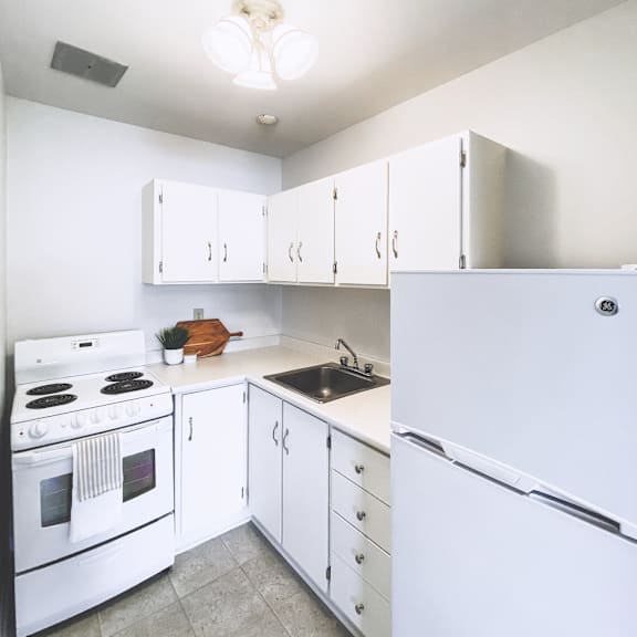 a white kitchen with a refrigerator, stove, and cabinets.