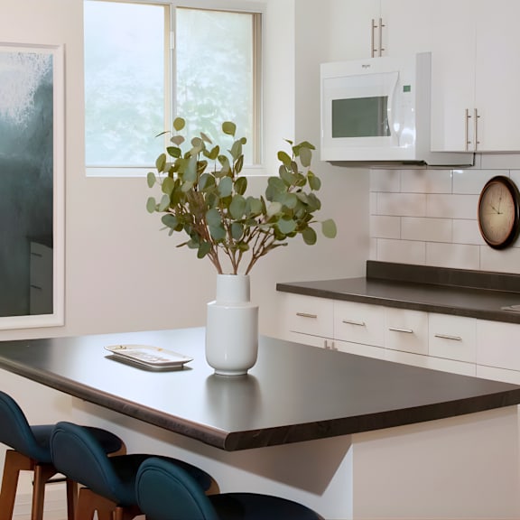 a kitchen with a table, chairs, and a vase of flowers.