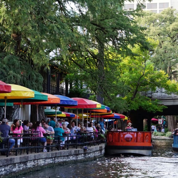 people sitting at restaurants next to a river