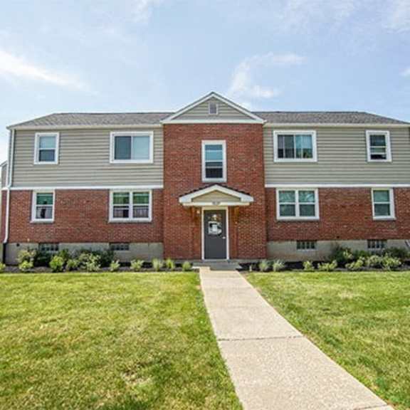 a brick building with a front yard and a walkway leading to the front door.