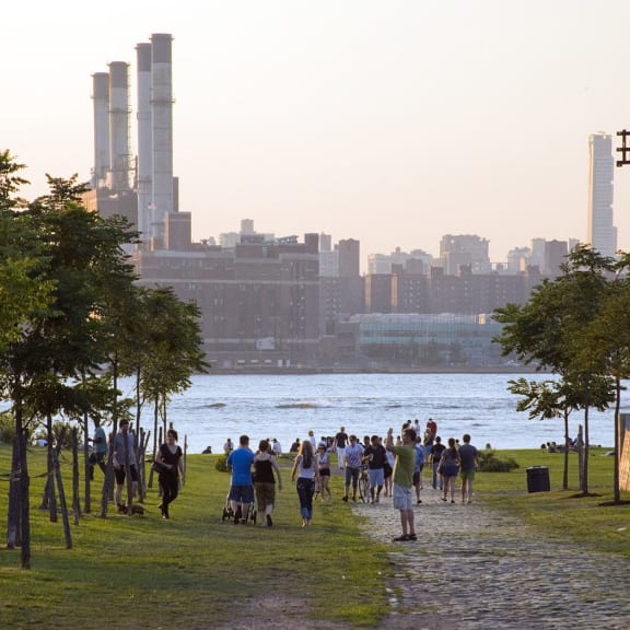 people walking on a path near the water with a city in the background at 34 Berry, Brooklyn, New York