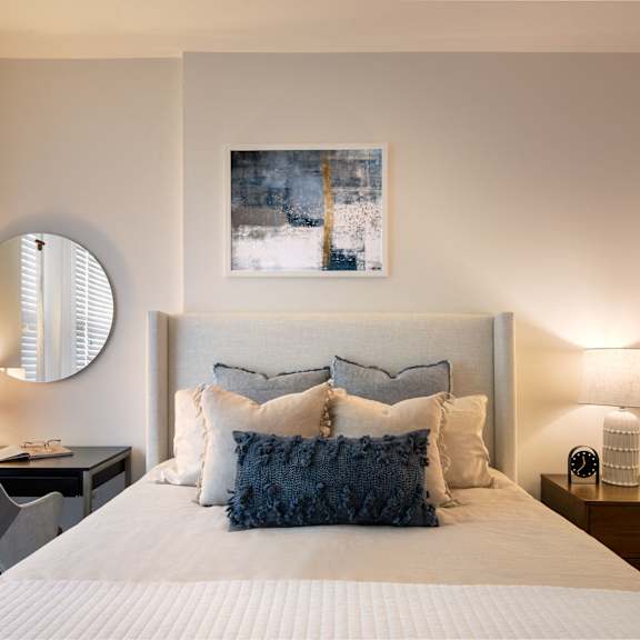 A bedroom with a large bed, a desk with a chair, and a painting on the wall.