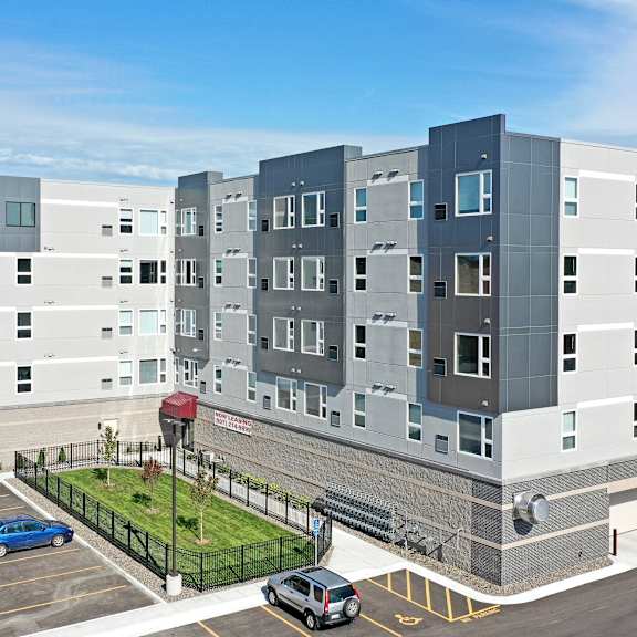a modern multi-story building with a parking lot in front.