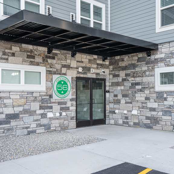 a stone building with a glass door and a green sign on it